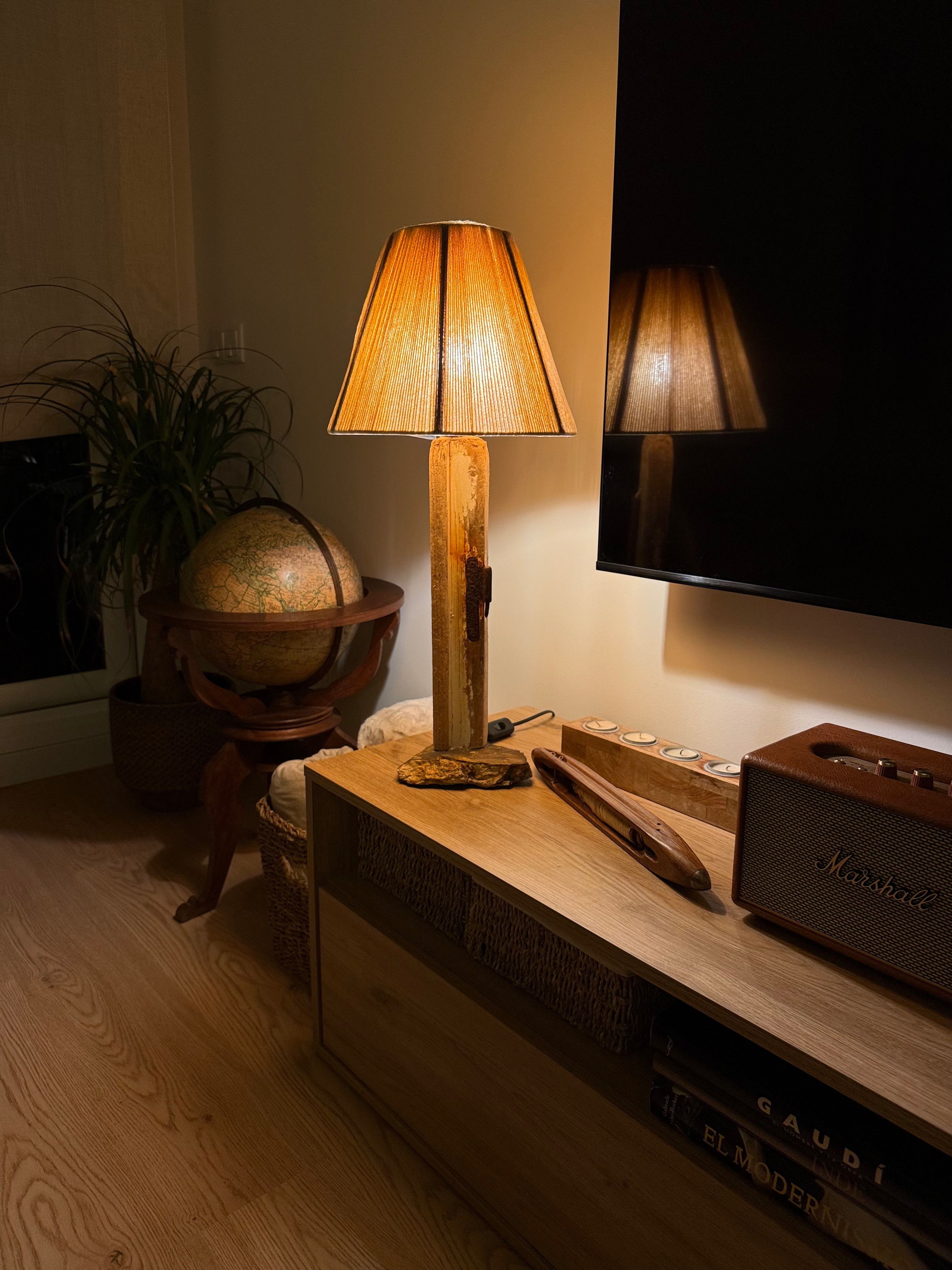 Lámpara con bisagra oxidada, piedra rojiza y pantalla de cordón pelirroja